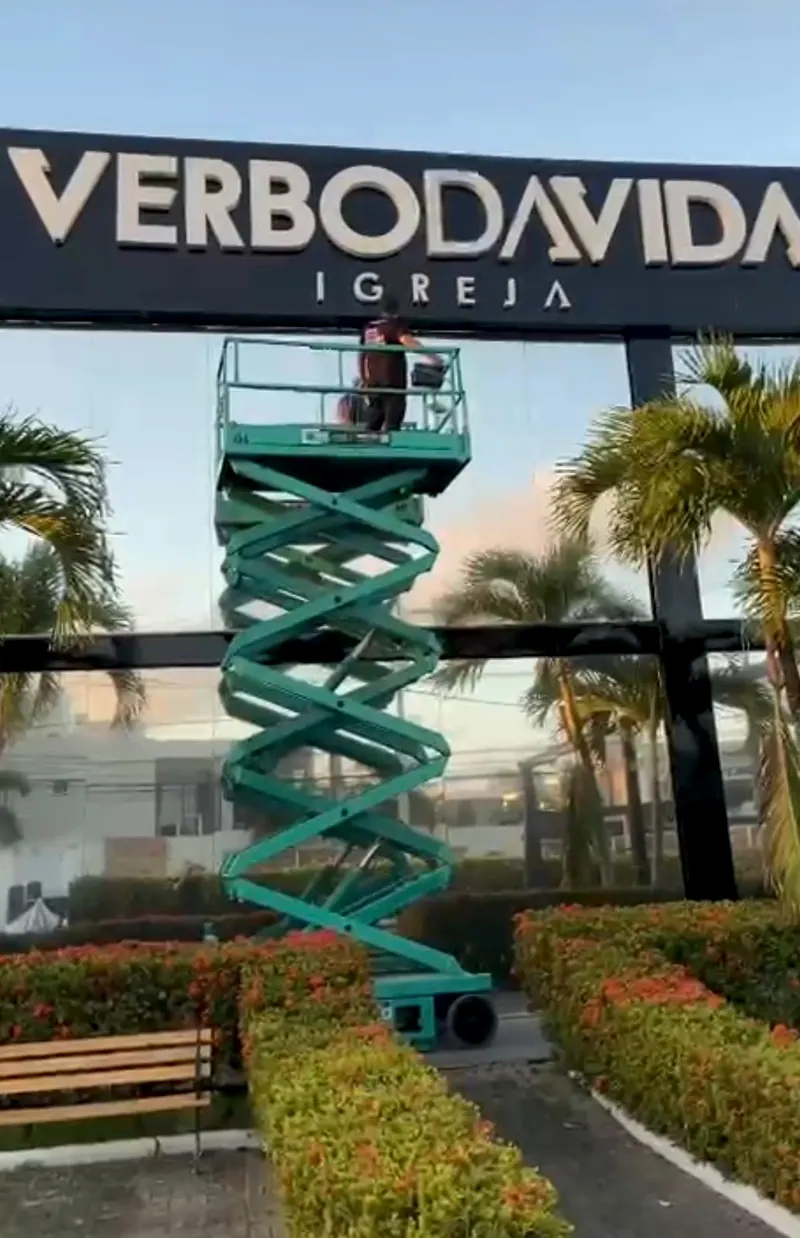 Plataforma tesoura estendida até o alto, em frente ao letreiro de uma igreja